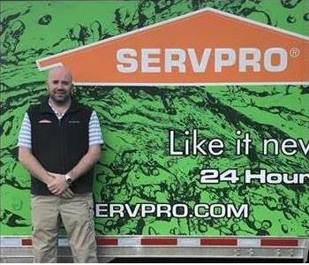 A man standing in front a large lime green trailer that says SERVPRO